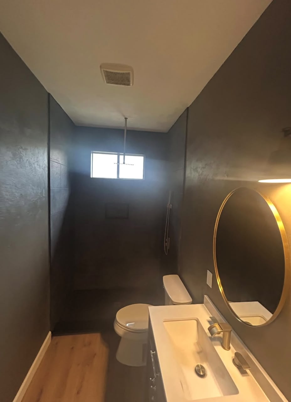 Dark moody bathroom with walk-in shower and gold mirror