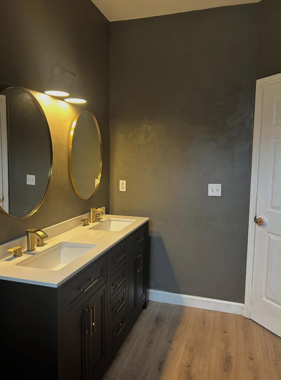Dark bathroom with dual vanity and gold fixtures